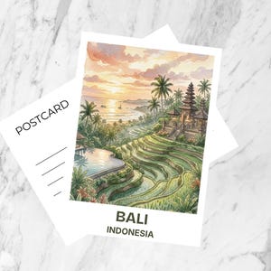 Può includere: Cartolina acquerellata con un tramonto su Bali, Indonesia. L'immagine mostra un tempio, terrazze di riso e palme. La parola "POSTCARD" è stampata su una carta bianca e "BALI INDONESIA" è stampata sulla cartolina.