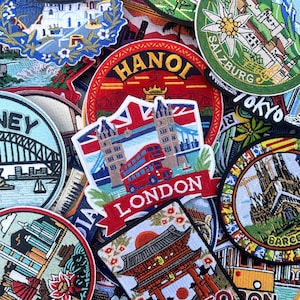 Puede incluir: Un conjunto de parches de viaje bordados con monumentos emblemáticos y nombres de ciudades. Los parches incluyen "Sydney" con la Ópera, "London" con un autobús rojo y el Tower Bridge, y "Hanoi".