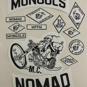Op de afbeelding: Een verzameling geborduurde patches in zwart en wit. Het woord "MONGOLS" staat prominent afgebeeld. Andere patches tonen "NOMAD", "MFFM" en een motorrijder op een motor. Diverse teksten en symbolen zijn ook aanwezig.