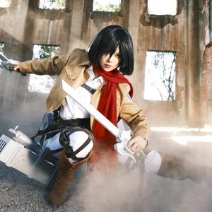 May include: A cosplay costume featuring a tan jacket, white collared shirt, white pants, and a bright red scarf. The outfit includes brown boots and a silver-colored mechanical harness with two metallic swords held in a dynamic combat pose.