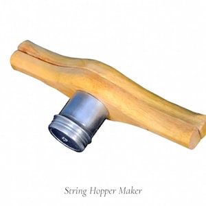 May include: A string hopper maker with a light wood handle and a silver metal base. The handle is a light brown color and has a unique shape. The text "String Hopper Maker" is below the object.
