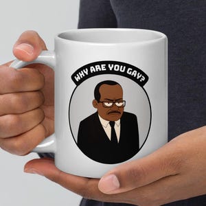 Könnte beinhalten: Weiße Keramik-Tasse mit einer Cartoon-Illustration eines Mannes im Anzug mit Brille und ernstem Gesichtsausdruck. Der Text "WHY ARE YOU GAY?" ist in einem Kreis angeordnet.