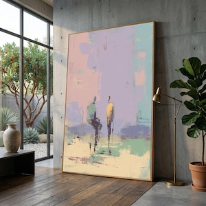 Könnte beinhalten: Abstrakter Kunstdruck mit zwei silhouettenhaften Figuren in einer sanften Pastellpalette aus Rosa, Lila, Grün und Gelb. Das Kunstwerk ist in einem goldfarbenen Rahmen gefasst und lehnt an einer Betonwand. Das Gemälde steht auf einem Holzboden.