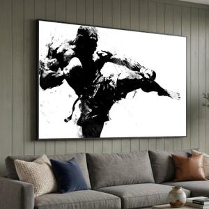 Pode incluir: Uma grande impressão de arte de parede retangular com uma ilustração em tinta preta e branca de alto contraste de um artista marcial realizando um chute lateral dinâmico. A figura é renderizada em pinceladas abstratas e salpicadas.