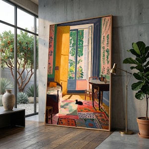 May include: A framed painting depicting a vibrant interior scene with a window overlooking a garden. The artwork features a colorful rug, a black cat, and a table. The painting is displayed in a modern room with a large window and a potted plant.