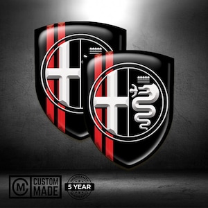 Può includere: Due emblemi neri a forma di scudo con strisce rosse e un disegno a croce bianca. Un emblema presenta un serpente bianco in un cerchio. Sono visibili anche i testi "CUSTOM MADE" e "5 YEAR WARRANTY".