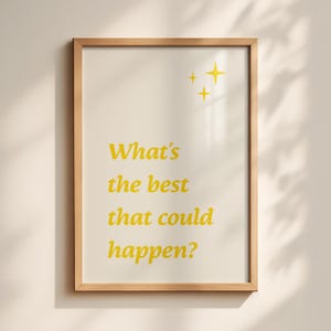 Op de afbeelding: Een ingelijste wandkunstprint met de gele tekst "What's the best that could happen?" gecentreerd op een lichtcrème achtergrond. Drie kleine gele vierpuntige sterpictogrammen zijn boven de tekst in de rechterbovenhoek geplaatst.