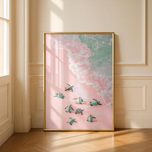 Pode incluir: Impressão artística emoldurada com uma praia rosa com ondas turquesas e tartarugas marinhas bebês. A moldura dourada realça a cena costeira. Várias tartarugas pequenas são visíveis, criando um ambiente tranquilo.