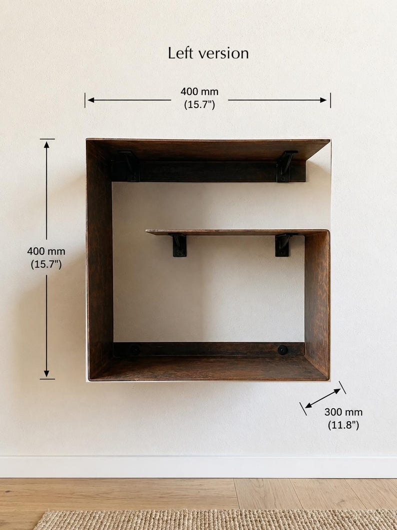May include: A wooden wall shelf with a square design. The shelf is 15.7 inches high and wide, and 11.8 inches deep. The shelf has a dark brown finish and is mounted on a white wall. The text "Left version" is at the top.