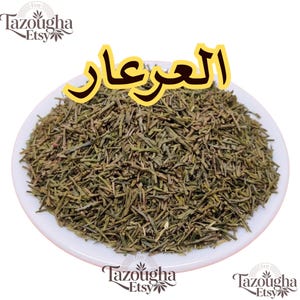 May include: A mound of dried, needle-like green herbs piled on a white plate. The Arabic text "العرعار" is displayed in large yellow letters with a black outline above the herbs. The Tazougha Etsy logo appears in the corners of the image.
