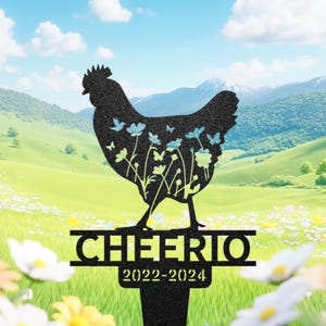 May include: Black metal garden stake featuring a silhouette of a hen with floral and butterfly cutouts. The stake reads "CHEERIO" above "2022-2024". The background shows a green field, flowers, and mountains.