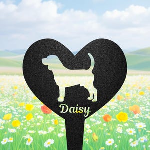 Puede incluir: Un estaca de jardín en forma de corazón negro con una silueta recortada de un perro en el centro. El nombre Daisy está impreso en una fuente cursiva de color claro debajo de la silueta del perro. La superficie del corazón tiene un acabado texturizado.