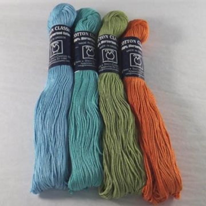 May include: Four skeins of cotton yarn in blue, teal, green, and orange colours. The yarn is labelled "Cotton Classic 100% Peruvian Cotton" and is made in Peru.