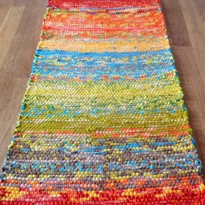 May include: A colorful woven rug with a rainbow pattern and orange fringe. The rug is made of recycled materials and is perfect for adding a touch of color to any room.