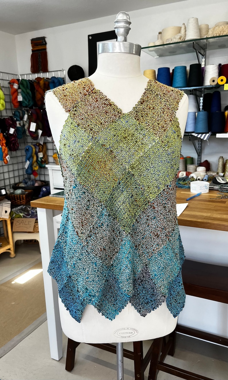 May include: A sleeveless, crocheted top with a V-neck and a diamond pattern in shades of brown, green, blue, and teal.