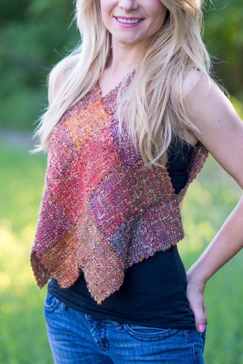 May include: A woman wearing a multi-colored sleeveless top with a black tank top underneath and blue jeans.