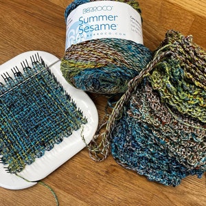 May include: A close-up of a loom with a woven fabric in shades of blue, green, and yellow. The yarn is in a skein with the label "Summer Sesame" and the brand name "Berroco".