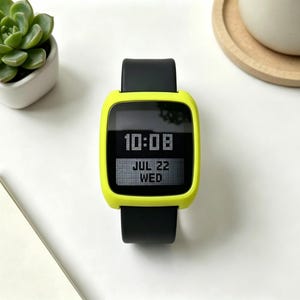 May include: A digital smartwatch with a bright neon yellow protective case and a smooth black silicone strap. The rectangular screen displays the time as 10:08 and the date as JUL 22 WED in a clear, white, pixelated digital font style.