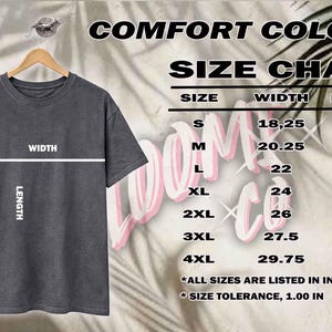 May include: A gray t-shirt hangs on a wooden hanger, with a size chart displayed to the right. The chart lists sizes S to 4XL, with width and length measurements in inches. The text "COMFORT COLORS" is at the top.