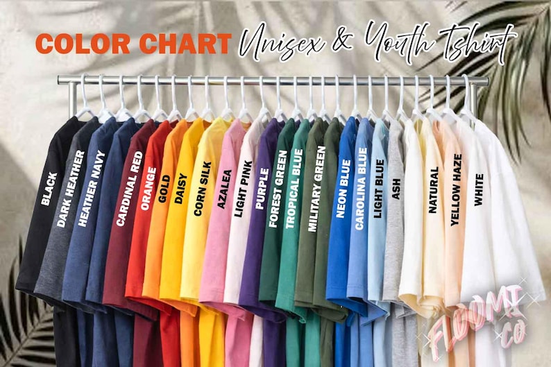 May include: A color chart of Unisex & Youth T-shirts in various colors, including black, navy, red, orange, yellow, pink, purple, green, blue, and white. Each shirt is labeled with its color name. The shirts are hanging on a metal rack.