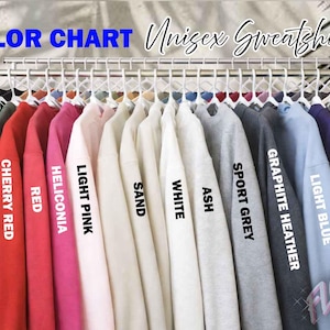 May include: A color chart of unisex sweatshirts in various colors, including military green, cherry red, and navy. The text "COLOR CHART" and "Unisex Sweatshirt" are visible. Each sweatshirt is hanging on a rack, showcasing the available color options.