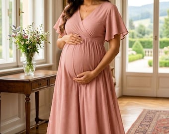 May include: A floor-length dusty rose maternity dress featuring a V-neckline, short flutter sleeves, and a wrap-style bodice. The fabric has a subtle textured dot pattern throughout, with a flowing skirt that drapes to the floor.