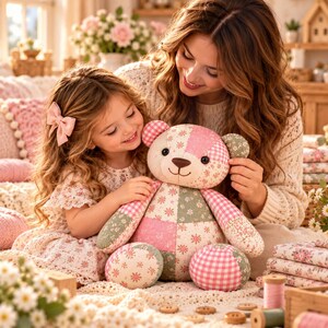 May include: A patchwork teddy bear constructed from various fabric patterns including pink gingham, sage green floral, and cream-coloured floral prints. The stuffed animal features a round head, two ears, two arms, and two legs, all stitched together.