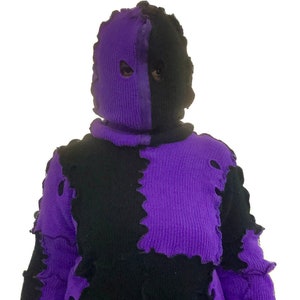 以下が含まれることがあります： 黒と紫のジャガード織りのセーターで、不規則なパッチワークのデザインになっています。セーターはハイネックで長袖です。セーターは一部ほつれており、下のニット生地が見えています。