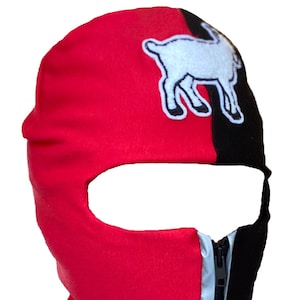May include: A red and black balaclava with a white goat design on the top. The balaclava has a zipper on the side.