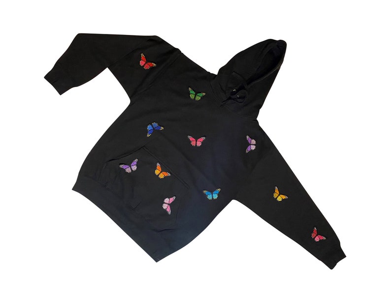May include: Black hoodie with a colorful butterfly pattern. The hoodie has a drawstring hood and a kangaroo pocket.