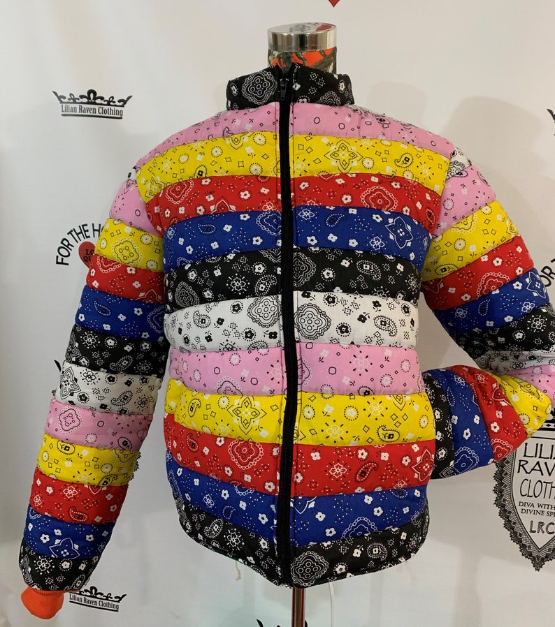 May include: A colorful puffer jacket with a bandana print. The jacket has a zipper closure and is made of a quilted fabric. The jacket is available in a variety of colors, including red, blue, yellow, and black.