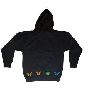 May include: Black hooded sweatshirt with a row of colorful butterfly appliques on the bottom hem.