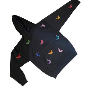 May include: Black hoodie with a rainbow butterfly design. The hoodie has a hood and a kangaroo pocket.