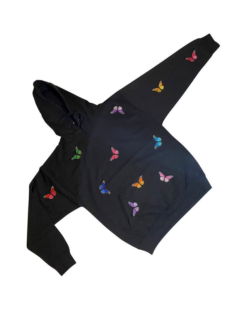 May include: Black hoodie with a rainbow butterfly design. The hoodie has a hood and a kangaroo pocket.