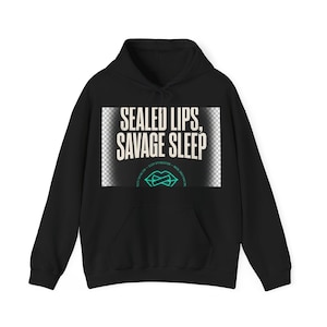 May include: A black hooded sweatshirt featuring a rectangular graphic on the chest. The graphic displays the text "SEALED LIPS, SAVAGE SLEEP" in a bold, light-colored font above a teal-colored icon of lips with a horizontal line across them.
