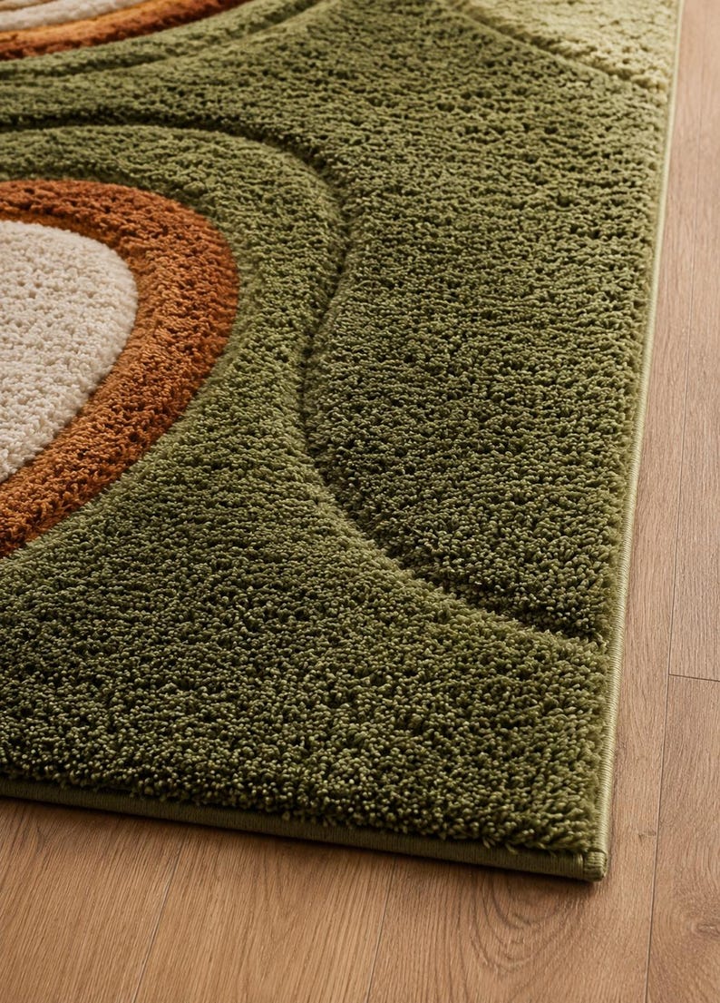 May include: A rectangular area rug featuring a high-pile, shaggy texture with a geometric pattern of concentric semi-circles. The design incorporates shades of olive green, burnt orange, and cream, creating a layered, textured visual effect.