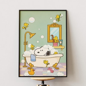 May include: A framed print featuring Snoopy in a bathtub with Woodstock and bubbles. The illustration has a light green background with a gold shower head and mirror. A yellow rubber duck and pink soap are also visible.