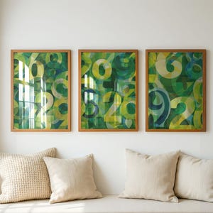 Puede incluir: Tres impresiones artísticas enmarcadas con un diseño de números verdes y amarillos. La obra de arte se exhibe sobre un banco con cojines beige. Los marcos son de color marrón claro.
