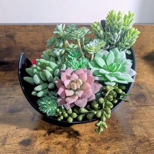 Puede incluir: Un letrero de madera hecho a mano con el texto "Welcome to our home" en un estilo manuscrito. El letrero está pintado de blanco con un acabado envejecido, y una pequeña hoja verde está sujeta en la parte superior. El letrero mide aproximadamente 30 cm de ancho.