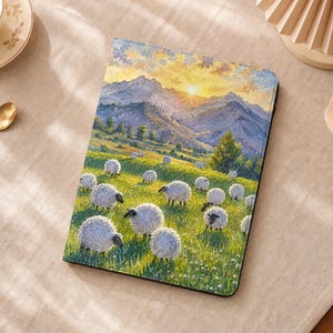 Puede incluir: Una funda rectangular para tableta con una ilustración de paisaje impresa de un rebaño de ovejas blancas pastando en un prado verde. El fondo muestra montañas bajo un cielo de amanecer amarillo brillante con nubes suaves.