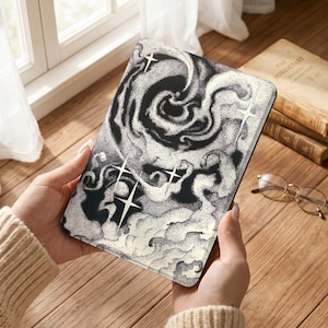 May include: A rectangular e-reader case featuring a black and white stippled illustration of a swirling galaxy or nebula with several four-pointed star shapes scattered across the surface, creating a high-contrast celestial design.