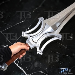 May include: A silver sword with a decorative hilt and a brown leather-wrapped handle. The blade is long and pointed, with a polished finish. The hilt features intricate designs and a small inscription. The sword is a prop or collectible item.