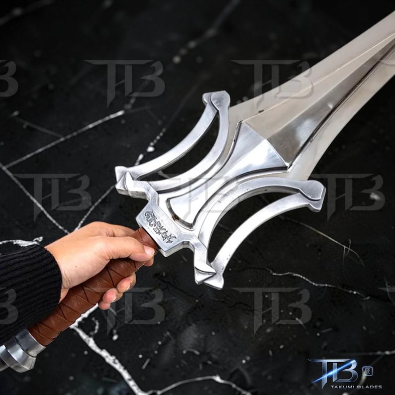 May include: A silver sword with a decorative hilt and a brown leather-wrapped handle. The blade is long and pointed, with a polished finish. The hilt features intricate designs and a small inscription. The sword is a prop or collectible item.