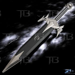 May include: A sword with a black blade featuring a silver metal tip and a complex silver crossguard. The handle is wrapped in black and silver bands, topped with a spherical pommel. A small silver emblem is centered on the black blade surface.