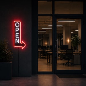Op de afbeelding: Een verticaal neonbord gemonteerd op een donkere buitenmuur met het woord OPEN in witte letters, omringd door een rode rechthoekige rand die eindigt in een pijl naar rechts. Het bord licht fel op tegen de donkere gevel van het gebouw.
