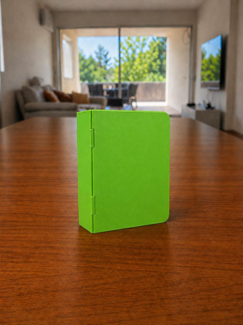 Puede incluir: Un estuche rectangular de color verde lima brillante con un acabado mate suave y una bisagra vertical en el lado izquierdo. El objeto se mantiene en posici&oacute;n vertical, con un exterior liso y s&oacute;lido, esquinas redondeadas y un dise&ntilde;o funcional.