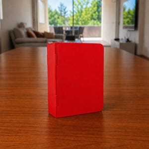 Puede incluir: Una caja rectangular de color rojo vibrante con un acabado mate y liso. El objeto presenta una bisagra vertical en el lado izquierdo, lo que sugiere un mecanismo de apertura. El dise&ntilde;o es sencillo, con bordes limpios y un color uniforme.