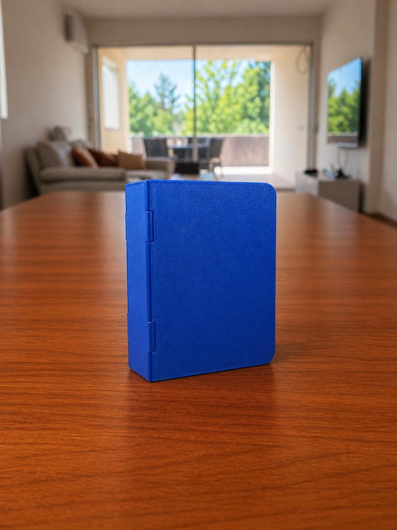 Puede incluir: Una caja de almacenamiento rectangular de color azul s&oacute;lido con un acabado mate suave y un panel lateral con bisagras. El objeto se mantiene en posici&oacute;n vertical sobre su base, con un color uniforme y un dise&ntilde;o funcional con bisagras visibles.