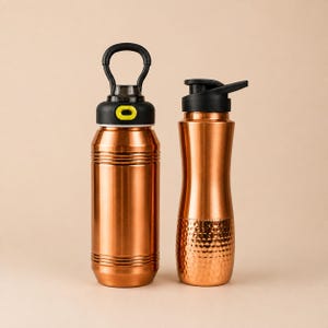 Op de afbeelding: Twee koperkleurige metalen waterflessen. De linkerfles heeft horizontale ribbels en een zwarte dop met een draaglus en gele knop. De rechterfles heeft een glad bovenstuk en een gehamerde textuur aan de onderkant met een zwarte klapdeksel.