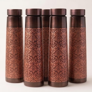 Könnte beinhalten: Fünf zylindrische Wasserflaschen aus Metall, die in einer Reihe angeordnet sind. Jede Flasche hat ein dunkel kupferfarbenes Finish mit einer gebürsteten Textur am Verschluss und ein detailliertes, florales Damastmuster auf dem Körper.